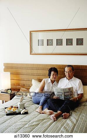 Older couple lying on bed, reading newspaper View Large Photo Image Stock Image - Older couple lying on bed, reading newspaper. Fotosearch