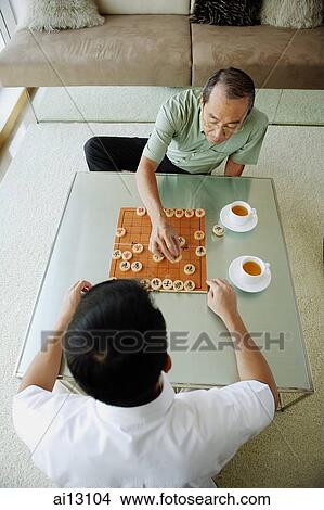 Older man playing Chinese chess with younger man View Large Photo Image Picture - Older man playing Chinese chess with younger man. Fotosearch
