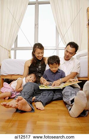 Parents reading with son, daughter looking at camera View Large Photo Image Stock Photo - Parents reading with son, daughter looking at camera. Fotosearch