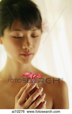 Stock Photograph - Portrait of a young woman, holding a flower. Fotosearch