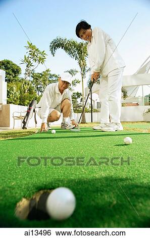 Senior couple playing golf, woman with golf club, man crouching down View Large Photo Image Stock Photograph - Senior couple playing golf, woman with golf club, man crouching down. Fotosearch