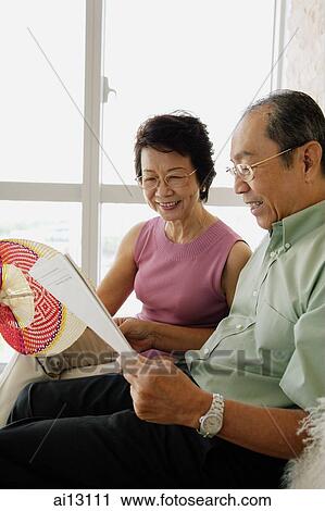 Senior couple sitting down, woman holding fan, man reading paper View Large Photo Image Stock Image - Senior couple sitting down, woman holding fan, man reading paper. Fotosearch