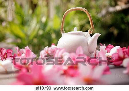 Stock Image - Still life of teapot surrounded by flowers. Fotosearch