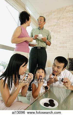 Three generation family in living room, eating cookies and drinking tea View Large Photo Image Stock Photograph - Three generation family in living room, eating cookies and drinking tea. Fotosearch