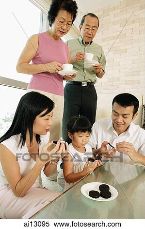 Three generation family in living room, eating cookies, grandparents standing, holding cups and saucers View Large Photo Image Stock Photography - Three generation family in living room, eating cookies, grandparents standing, holding cups and saucers. Fotosearch