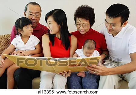 Three generation family, sitting side by side and looking at photo album View Large Photo Image Stock Photography - Three generation family, sitting side by side and looking at photo album. Fotosearch