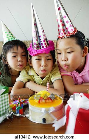 Three girls with party hats blowing candle on birthday cake View Large Photo Image Stock Image - Three girls with party hats blowing candle on birthday cake. Fotosearch