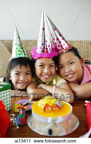 Three girls with party hats in front of birthday cake View Large Photo Image Stock Image - Three girls with party hats in front of birthday cake. Fotosearch