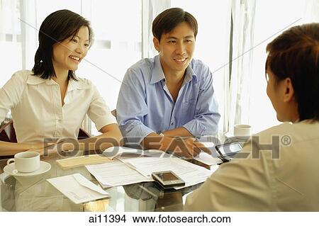 Three people sitting at table, face to face View Large Photo Image Picture - Three people sitting at table, face to face. Fotosearch
