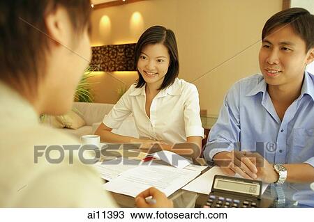 Three people sitting at table, calculator and papers in front of them View Large Photo Image Stock Image - Three people sitting at table, calculator and papers in front of them. Fotosearch