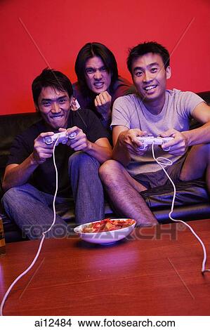 Three young men, playing video games View Large Photo Image Picture - Three young men, playing video games. Fotosearch