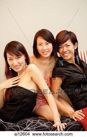 Picture - Three young women, sitting side by side, looking at camera. Fotosearch