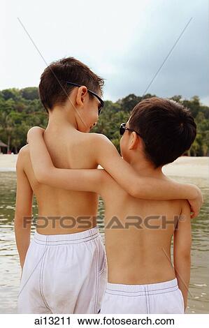 Stock Image - Two boys, arm around each other, rear view. Fotosearch
