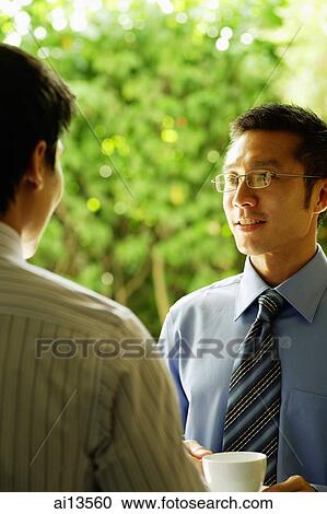 Two businessmen standing face to face, talking View Large Photo Image Stock Image - Two businessmen standing face to face, talking. Fotosearch