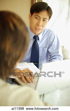 Stock Photo - Two executives having a discussion, laptop open in front of them. Fotosearch