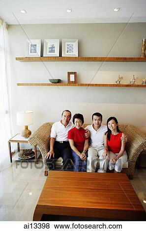 Stock Photo - Two generation family, sitting in living room, looking at camera. Fotosearch