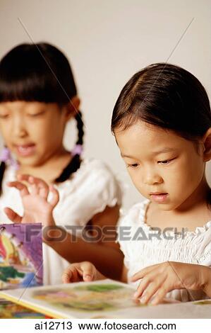 Two girls looking at books side by side View Large Photo Image Stock Image - Two girls looking at books side by side. Fotosearch