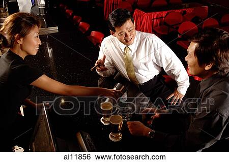 Two men at bar counter, bartender pouring drinks View Large Photo Image Stock Photograph - Two men at bar counter, bartender pouring drinks. Fotosearch