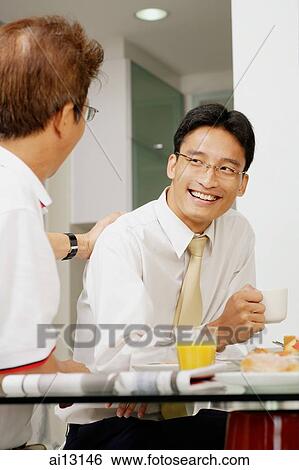 Two men having breakfast, sitting side by side View Large Photo Image Stock Photograph - Two men having breakfast, sitting side by side. Fotosearch