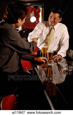 Two men shaking hands, beer glasses on table. View Large Photo Image Stock Photo - Two men shaking hands, beer glasses on table.. Fotosearch