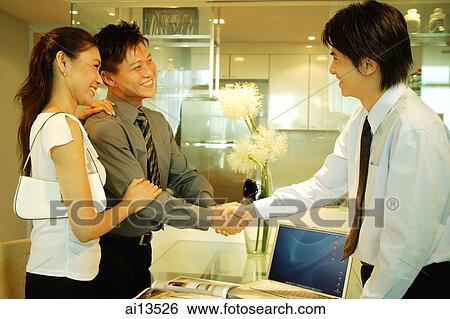 Two men shaking hands, woman holding arm of one of the man View Large Photo Image Stock Photograph - Two men shaking hands, woman holding arm of one of the man. Fotosearch