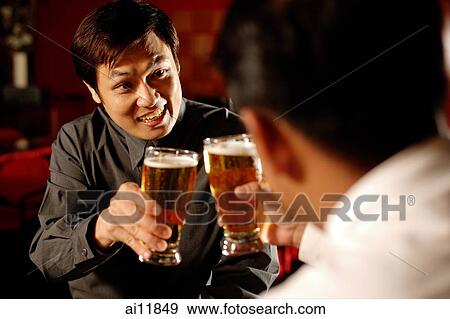 Two men toasting with beer glasses, over the shoulder view View Large Photo Image Stock Photo - Two men toasting with beer glasses, over the shoulder view. Fotosearch