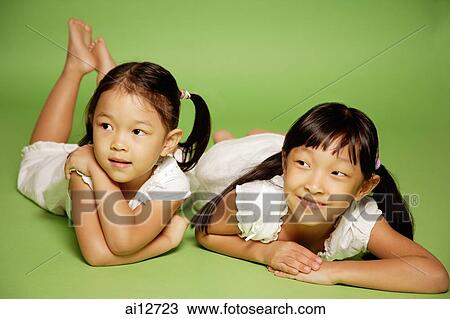 Stock Image - Two sisters lying side by side. Fotosearch