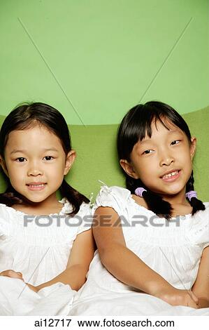 Two sisters sitting side by side View Large Photo Image Stock Photo - Two sisters sitting side by side. Fotosearch
