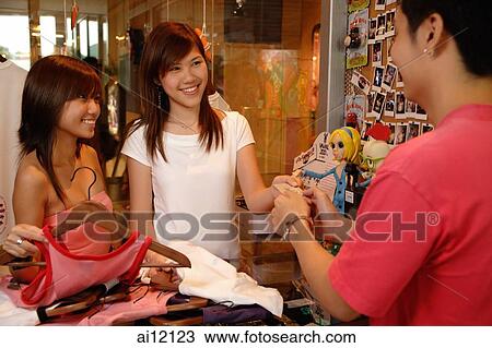 Two women at counter, making a purchase View Large Photo Image Stock Image - Two women at counter, making a purchase. Fotosearch