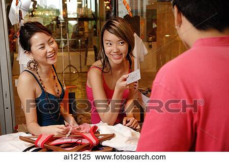Stock Photography - Two women at counter, making a purchase. Fotosearch