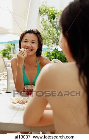 Two women facing each other at table, one eating View Large Photo Image Stock Photo - Two women facing each other at table, one eating. Fotosearch