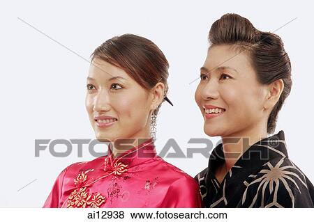 Stock Photo - Two women in traditional costumes, looking away, portrait. Fotosearch