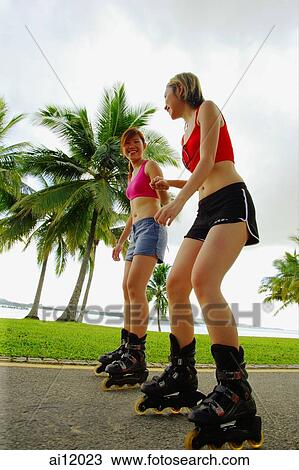 Stock Image - Two women inline skating at park. Fotosearch