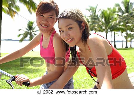 Two women on bicycles, looking at camera View Large Photo Image Stock Image - Two women on bicycles, looking at camera. Fotosearch