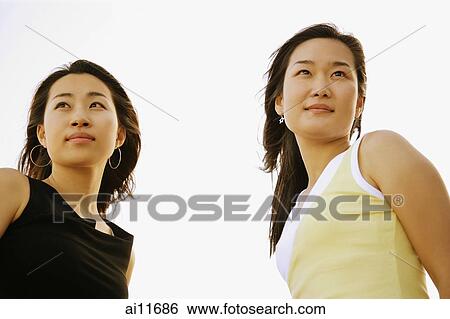 Two women, standing side by side, looking away View Large Photo Image Stock Photograph - Two women, standing side by side, looking away. Fotosearch