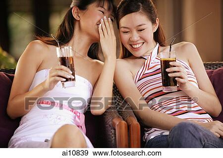 Two young women holding drinks, sitting side by side View Large Photo Image Stock Photo - Two young women holding drinks, sitting side by side. Fotosearch