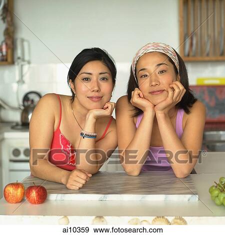 Two young women in kitchen, looking at camera View Large Photo Image Stock Photo - Two young women in kitchen, looking at camera. Fotosearch
