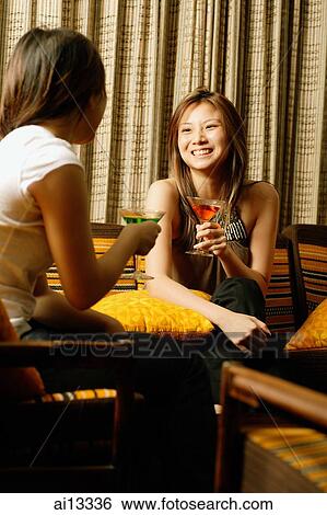 Two young women, in night club, holding drinks View Large Photo Image Stock Photograph - Two young women, in night club, holding drinks. Fotosearch
