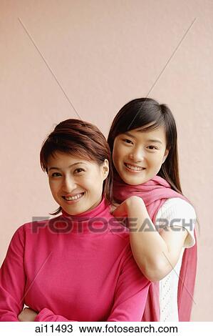 Stock Image - Two young women, looking at camera, smiling, portrait. Fotosearch