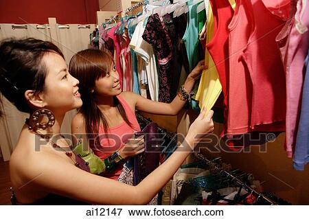 Two young women looking at clothes on clothes rack View Large Photo Image Stock Photo - Two young women looking at clothes on clothes rack. Fotosearch