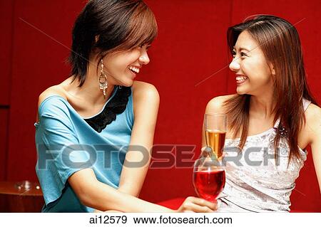 Two young women, with drinks, facing each other View Large Photo Image Stock Photo - Two young women, with drinks, facing each other. Fotosearch