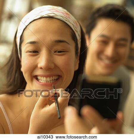 Woman applying lipstick, man in the background, looking on View Large Photo Image Stock Image - Woman applying lipstick, man in the background, looking on. Fotosearch