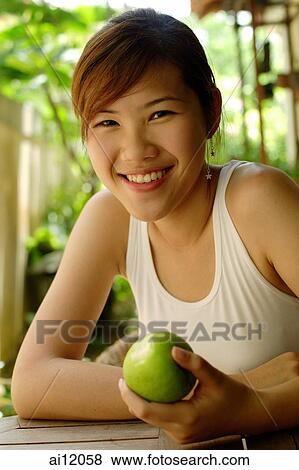 Woman holding an apple, looking at camera View Large Photo Image Stock Photo - Woman holding an apple, looking at camera. Fotosearch