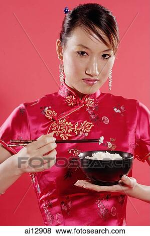 Woman holding bowl of rice and chopsticks, looking at camera View Large Photo Image Stock Photo - Woman holding bowl of rice and chopsticks, looking at camera. Fotosearch