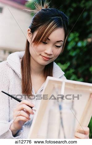 Woman holding brush and painting on canvas View Large Photo Image Stock Photograph - Woman holding brush and painting on canvas. Fotosearch