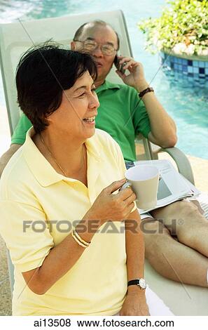 Woman holding coffee mug, man on lounge chair, using mobile phone View Large Photo Image Stock Photo - Woman holding coffee mug, man on lounge chair, using mobile phone. Fotosearch