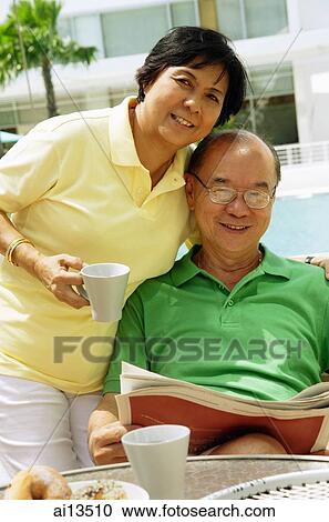 Woman holding coffee mug, man sitting down holding newspaper, looking at camera View Large Photo Image Stock Image - Woman holding coffee mug, man sitting down holding newspaper, looking at camera. Fotosearch
