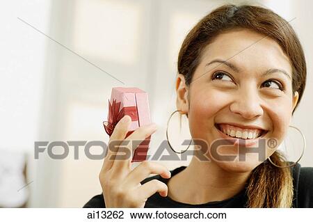 Woman holding gift box, looking away and smiling View Large Photo Image Stock Image - Woman holding gift box, looking away and smiling. Fotosearch