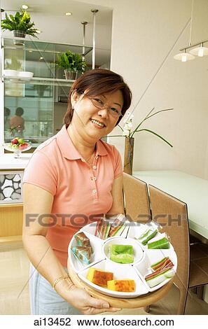 Woman holding tray of cakes, looking at camera View Large Photo Image Stock Image - Woman holding tray of cakes, looking at camera. Fotosearch