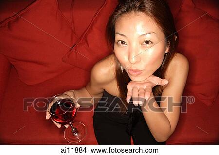Woman holding wine glass and blowing kiss at camera View Large Photo Image Picture - Woman holding wine glass and blowing kiss at camera. Fotosearch